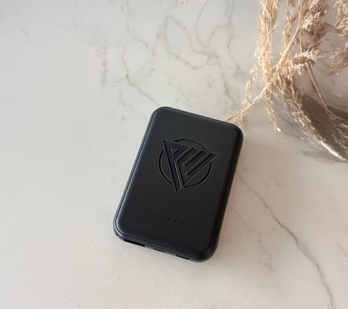 Black magnetic portable charger with slim, lightweight design shown charging a smartphone. This fast-charging power bank is ideal for travel, seniors, employees, teachers, or wedding gifts, available in blank or personalized engraved options.